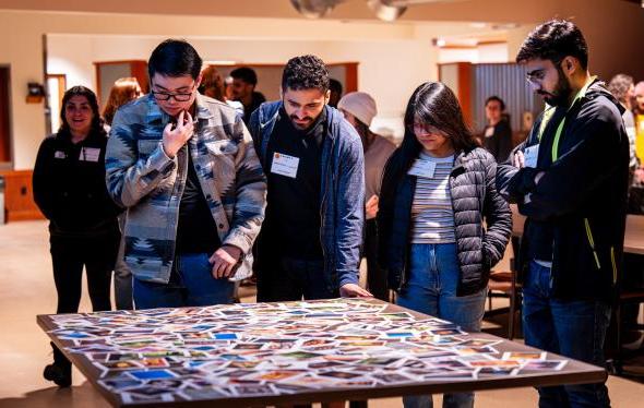 4 students walking up to choose a printed image from the table